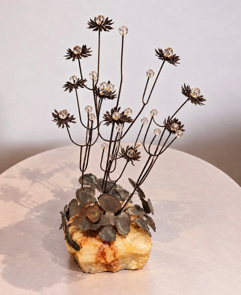 Angled view of branching metal flowers and clear beads above a rough stone base