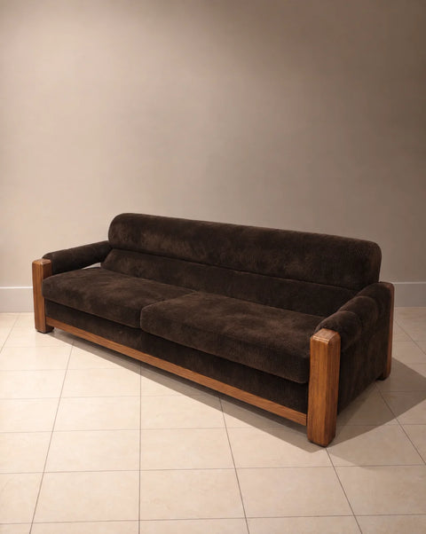 Angled view of chocolate brown velvet sofa with wood frame