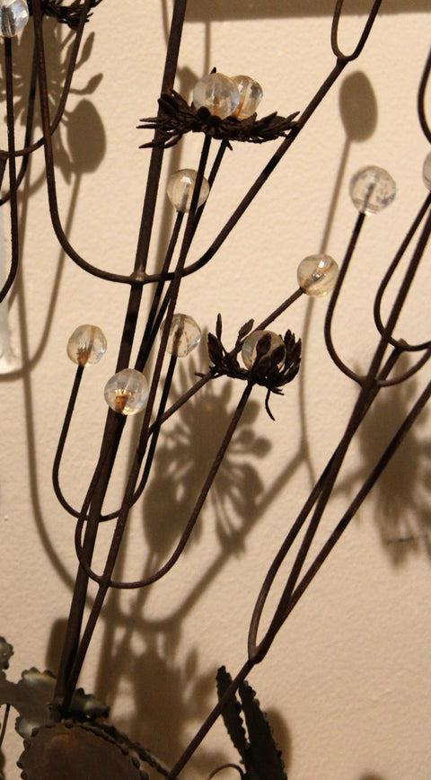 Close-up of clear beads and metal flowers casting shadows