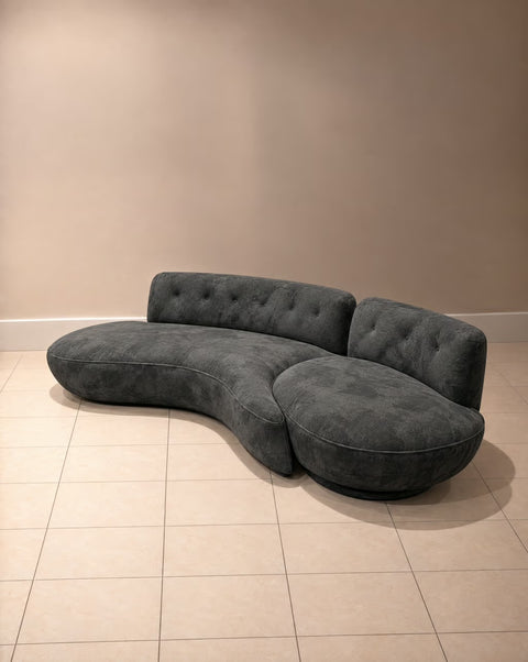 Three-quarter view of charcoal velvet sofa showing curved seat and rounded section