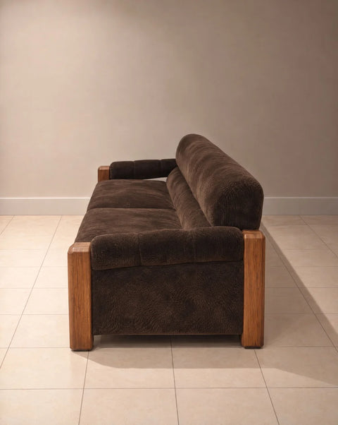 Side view of brown velvet sofa showing padded arm and wood front post