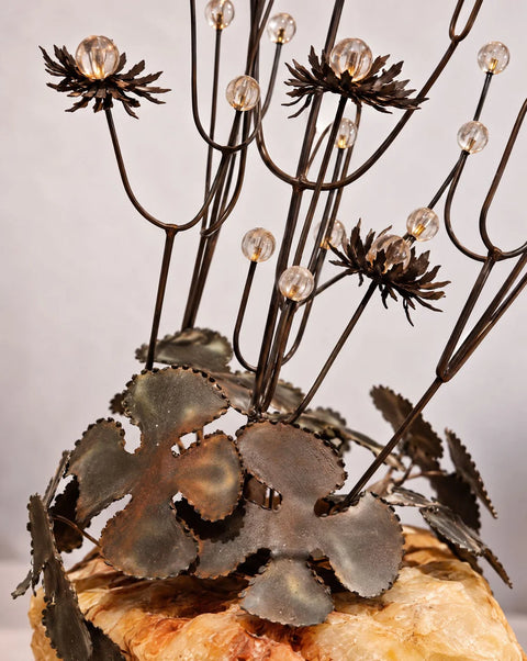 Detail of scalloped metal leaves, branching stems and cream-and-amber stone base