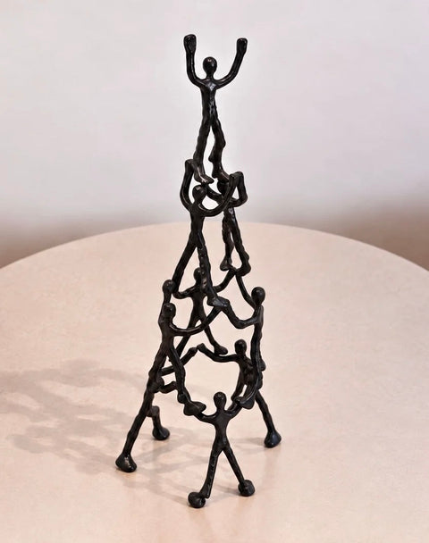 Black aluminum human pyramid sculpture on a round display table
