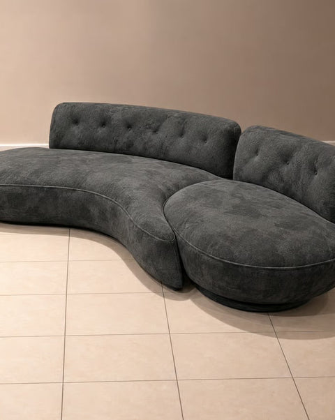Charcoal velvet sofa showing tufted backrests and curved seating