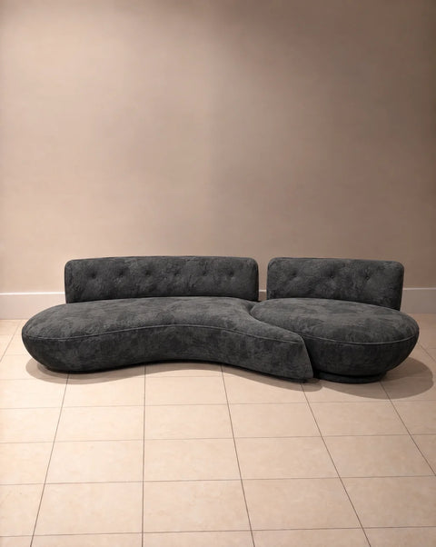 Angled front view of charcoal velvet sofa with curved seat and rounded companion section