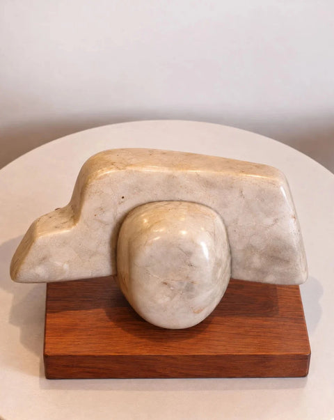 Angled view of the abstract marble sculpture and its wood plinth